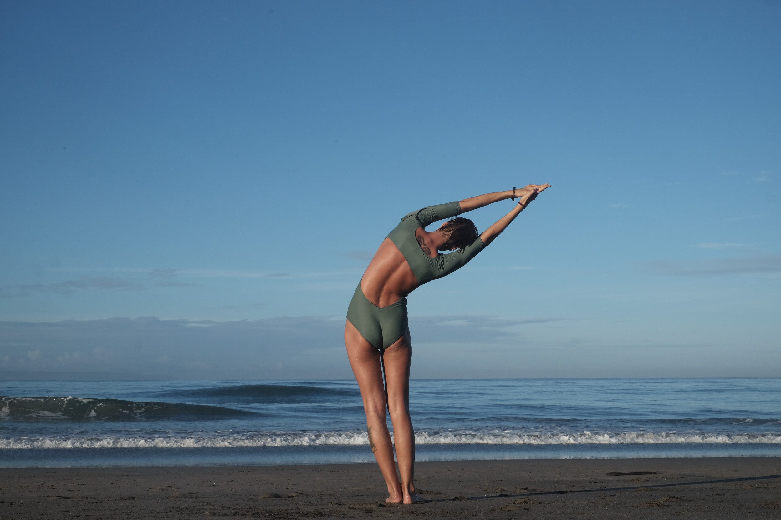 woman warming up with yoga poses before her surf session