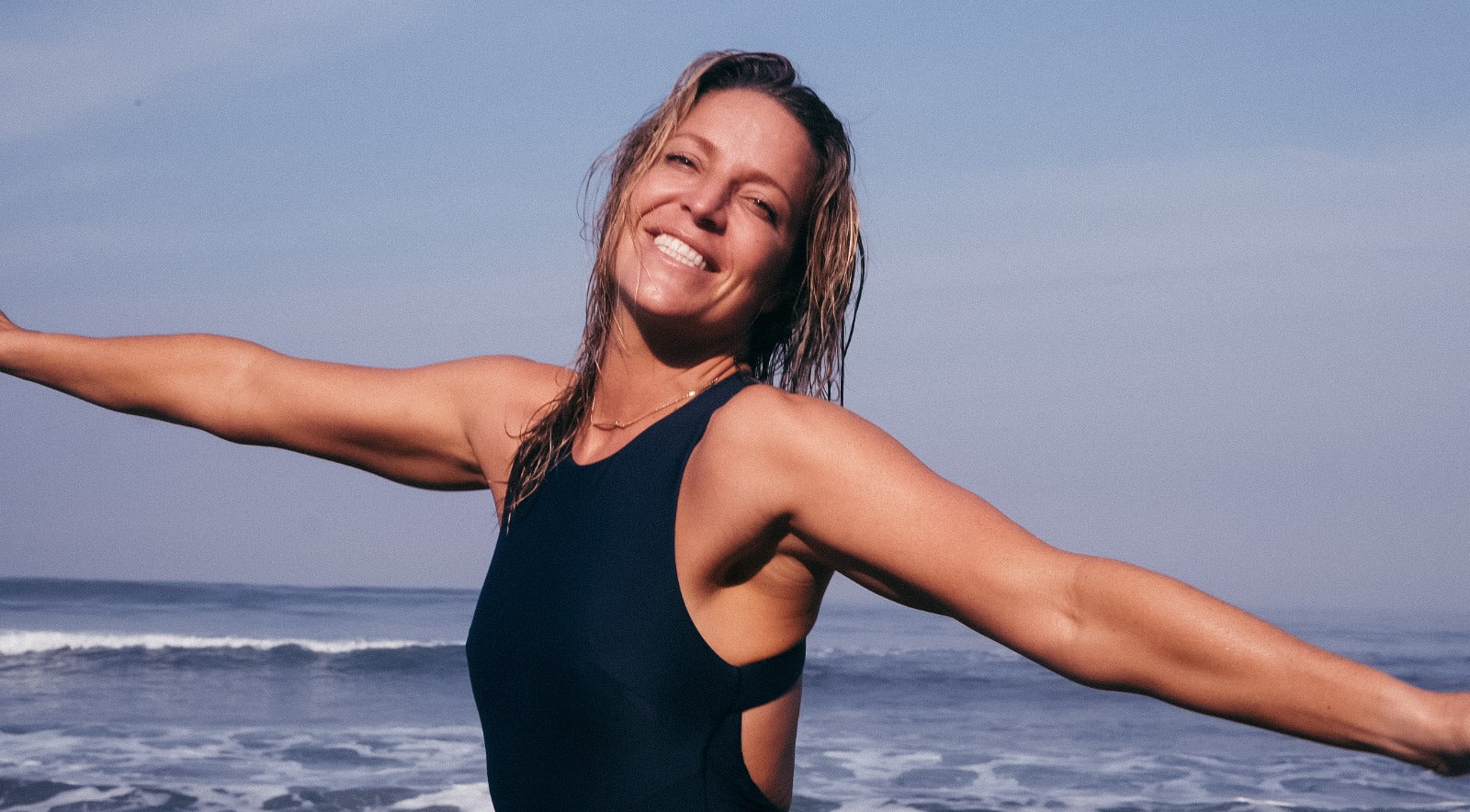 Jess laughing while wearing Canggu surf one piece in navy blue