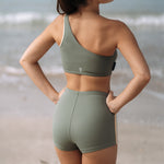 Woman wearing Ninefoot Studio Kongs one shoulder surf top in army green – asymmetric cut Italian recycled fabric bikini top designed for movement in Bali