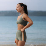 Woman wearing Ninefoot Studio Kongs one shoulder surf top in army green – asymmetric cut Italian recycled fabric bikini top designed for movement in Bali
