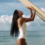 Krui Onepiece Surf Swimsuit in White with a long board o