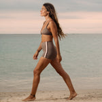 Woman wearing Ninefoot Studio teal recycled fabric surf bikini top with brown contrast trim – sustainable swimwear tested in real surf conditions in Bali