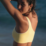 Woman wearing Ninefoot Studio Kongs one shoulder surf top in yellow– asymmetric cut Italian recycled fabric bikini top designed for movement in Bali