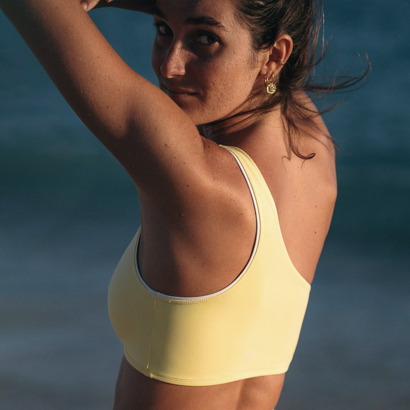 Woman wearing Ninefoot Studio Kongs one shoulder surf top in yellow– asymmetric cut Italian recycled fabric bikini top designed for movement in Bali