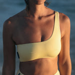 Woman wearing Ninefoot Studio Kongs one shoulder surf top in yellow– asymmetric cut Italian recycled fabric bikini top designed for movement in Bali