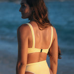 Woman wearing Ninefoot Studio teal recycled fabric yellow surf bikini top with white contrast trim – sustainable swimwear tested in real surf conditions in Bali