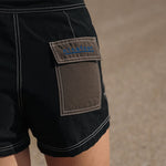 Woman wearing Ninefoot Studio black surf shorts with contrast stitching – mid-rise tailored fit quick-dry deadstock polyester twill ethically made in Bali