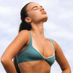 Woman wearing Ninefoot Studio teal recycled fabric surf bikini top with white contrast trim – sustainable swimwear tested in real surf conditions in Bali