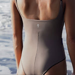 Woman wearing Ninefoot Studio sage tripoli one-piece swimsuit with brown contrast straps – scoop neck Italian recycled fabric surf swimwear made in Bali