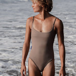 Woman wearing Ninefoot Studio sage tripoli one-piece swimsuit with brown contrast straps – scoop neck Italian recycled fabric surf swimwear made in Bali