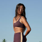 Woman wearing Ninefoot Studio Kongs one shoulder surf top in burgundy – asymmetric cut Italian recycled fabric bikini top designed for movement in Bali